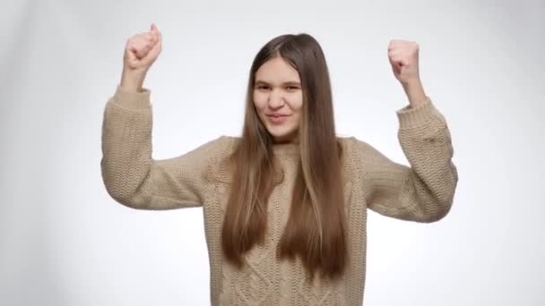 Gelukkig dansen en juichend meisje lachen en lachen vanwege succes of overwinning op witte studio achtergrond — Stockvideo