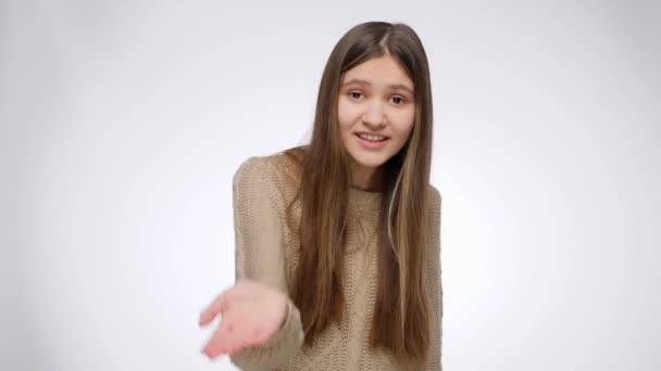 Retrato de menina sorridente acenando, chamando ou convidando você sobre fundo estúdio branco — Vídeo de Stock