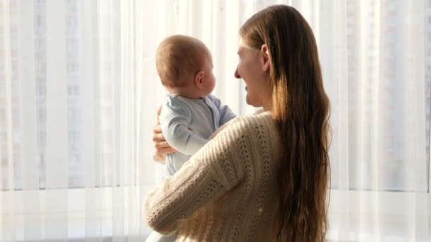 Lindo bebé mirando sonriente madre en gran dote en la luz del atardecer. Concepto de felicidad familiar y paternidad — Vídeos de Stock