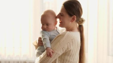 Gün batımında küçük oğluna sarılıp gülümseyen genç bir anne. Aile mutluluğu ve ebeveynlik kavramı