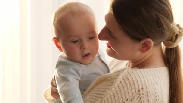 Mosolygó boldog anya portréja, amint arcon csókolja a kisfiát. A családi boldogság és nevelés fogalma — Stock videók