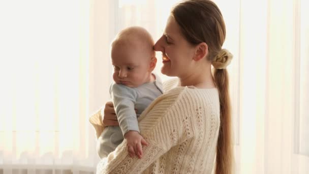 Joven madre abrazando y sonriendo a su pequeño hijo en la luz del atardecer. Concepto de felicidad familiar y paternidad — Vídeos de Stock