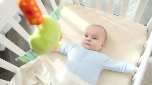 Point de vue de secouer jouet et de regarder le petit garçon couché dans le berceau dans la chambre à coucher. Concept de parentalité, bonheur familial et développement du bébé — Video