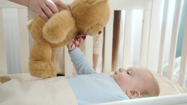可爱的小男孩看着妈妈抱着的玩具玩具玩具玩具熊。养育子女、家庭幸福和婴儿发展的概念 — 图库视频影像