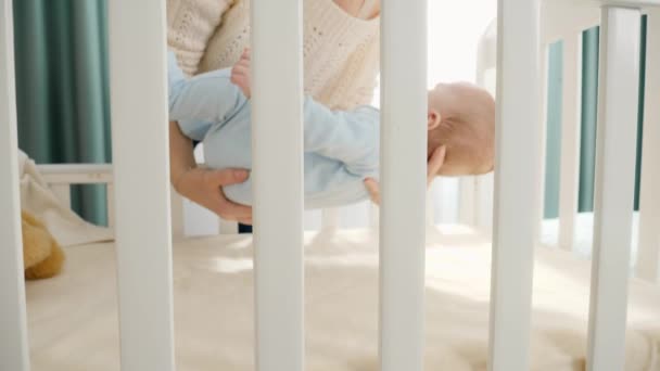 Young mother laying her little baby son in wooden cradle. Concept of parenting, family happy lifestyle and baby development — Stock Video