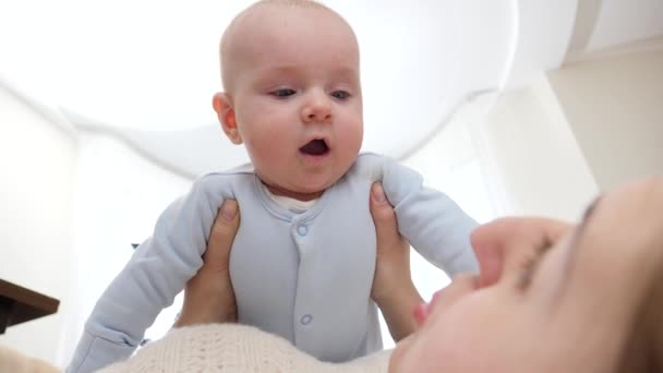 Portrait of young mother lying and holding her cute little baby son. Concept of family happiness and child development — Stock Video