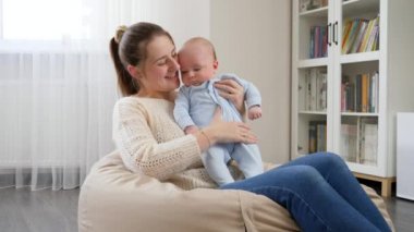 Güzel, gülümseyen bir anne ve küçük oğlu oturma odasında armut çuvalında oturuyor. Aile mutluluğu ve çocuk gelişimi kavramı