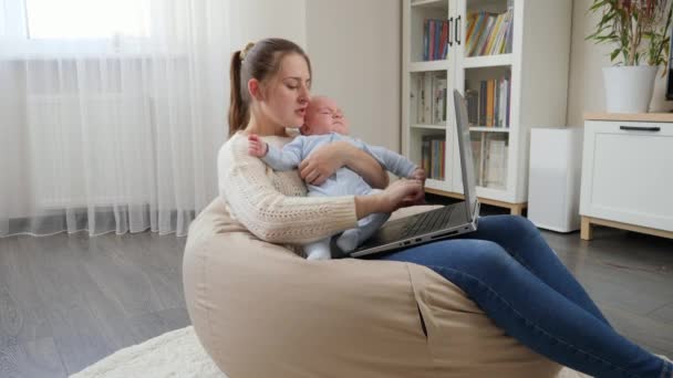 Weinendes Baby auf dem Schoß der Mutter, während sie von zu Hause aus am Laptop arbeitet. Fernarbeit während der Covid-19-Pandemie — Stockvideo