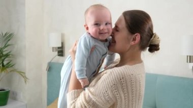 Mutlu gülüşler ve gülümseyen erkek bebek, annesini kucağında tutup sallarken ona bakıyor. Aile mutluluğu ve çocuk gelişimi kavramı
