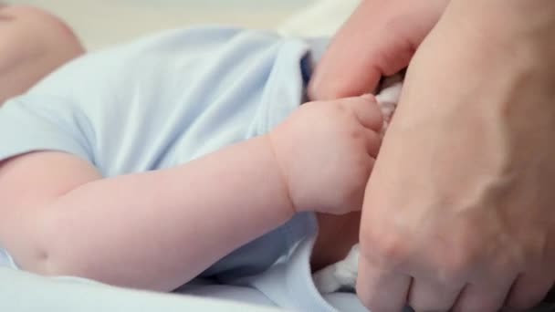 Fechar-se de mãe decolando e mudando fraldas bagunçadas de seu bebê deitado no berço. Conceito de pai, higiene do bebê e desenvolvimento infantil — Vídeo de Stock