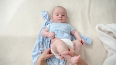 Annesinin bebek bezini değiştirdiği ve oğlunun yatakta yattığı pov. Ebeveynlik kavramı, bebek hijyeni ve çocuk gelişimi