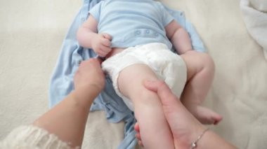 Bebek bezi değiştirme ve yatakta erkek bebeğin kıyafetlerini değiştirme. Ebeveynlik kavramı, bebek hijyeni ve çocuk gelişimi