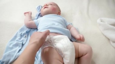 Annenin beşikteki yeni doğmuş bebeğiyle bebek bezi değiştirmesine yakın çekim. Ebeveynlik kavramı, bebek hijyeni ve çocuk gelişimi
