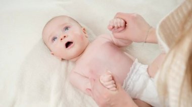 Anne, küçük oğluna masaj yapıyor ve jimnastik yapıyor. Ebeveynlik, bebek bakımı ve sağlık hizmetleri kavramı.