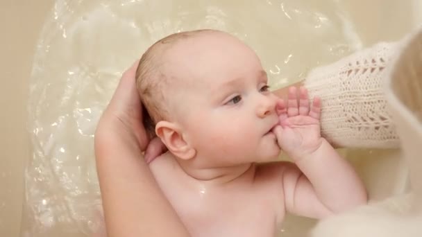 Carino bambino succhiare il dito mentre la madre lo lava nella vasca da bagno. Concetto di igiene, cura del bambino e assistenza sanitaria. — Video Stock