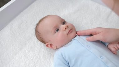 Annesi masaj yaparken ve onunla oynarken, sehpada uzanan tatlı bir erkek bebek. Hijyen, bebek bakımı ve sağlık hizmetleri kavramı