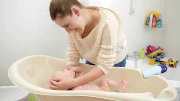 Boldog mosolygó anya mossa a kisfiát a fürdőszobában. A higiénia, a gyermekgondozás és az egészségügy fogalma — Stock videók