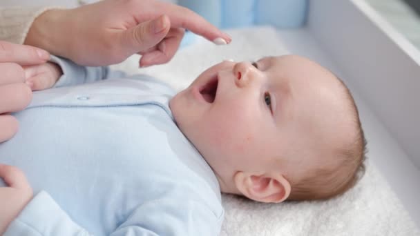 Carino bambino sdraiato sul tavolo da toeletta mentre la madre applica crema idratante e detergente. Concetto di igiene, cura del bambino e assistenza sanitaria — Video Stock