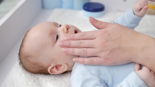 Annenin kuru deriyi önlemek için nemlendirici krem sürmesine yakın çekim. Hijyen, bebek bakımı ve sağlık hizmetleri kavramı — Stok video