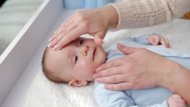 Mor använder kräm och lotion för att förhindra att hennes baby hud torkar. Begreppet hygien, barnomsorg och hälsovård — Stockvideo