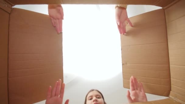 Две сестры-подростки удивились и удивились, открыв большую картонную коробку с посылкой. Волнение после получения посылки. — стоковое видео