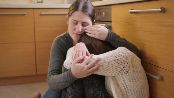 Aufgebrachtes weinendes Teenager-Mädchen auf dem Boden sitzend und Mutter umarmend. Konzept häuslicher Gewalt und familiärer Aggression und Teenager-Depressionen. — Stockvideo