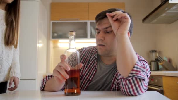 La hija adolescente tomando la botella con el alcohol del padre adicto bebiendo en la cocina. Problema de alcoholismo y adicción — Vídeos de Stock