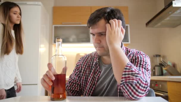 Chica joven abrazando y apoyando al hombre borracho bebiendo alcohol en la cocina. Problemas de alcoholismo y adicción — Vídeos de Stock