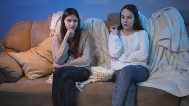 Две девушки разговаривают и обсуждают белое кино, смотрящее телевизор ночью — стоковое видео