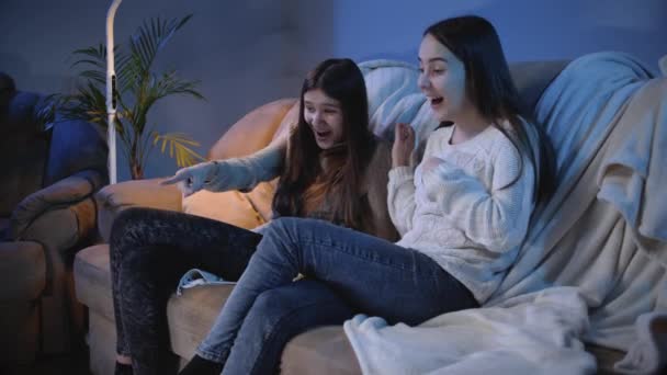 Duas garotas sorridentes rindo e sorrindo de filme engraçado de comédia na televisão à noite — Vídeo de Stock