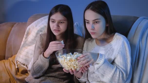 Chicas sonrientes felices disfrutando viendo programas de televisión y comiendo palomitas de maíz por la noche — Vídeos de Stock