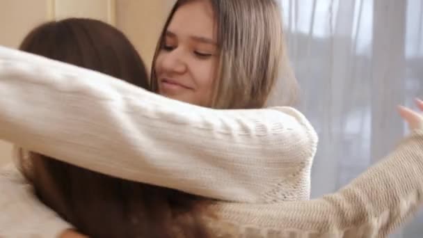 Портрет веселой улыбающейся девушки, обнимающей свою подругу после встречи в доме — стоковое видео