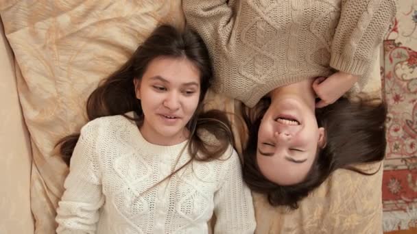 Retrato de niñas sonrientes felices hablando mientras se relaja en la cama en casa. Amistad y relación adolescente — Vídeo de stock