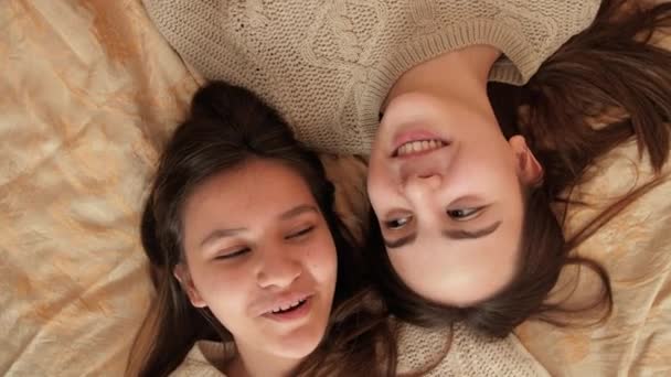 Kamera dreht sich um zwei Teenager-Mädchen, die auf dem Bett liegen und reden. Teenager-Freundschaft und Beziehung — Stockvideo