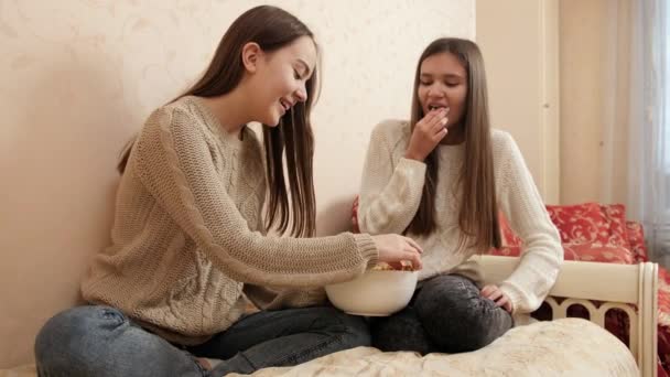 Dwie nastolatki rozmawiające w łóżku i jedzące popcorn. Nastoletnia przyjaźń i związek — Wideo stockowe