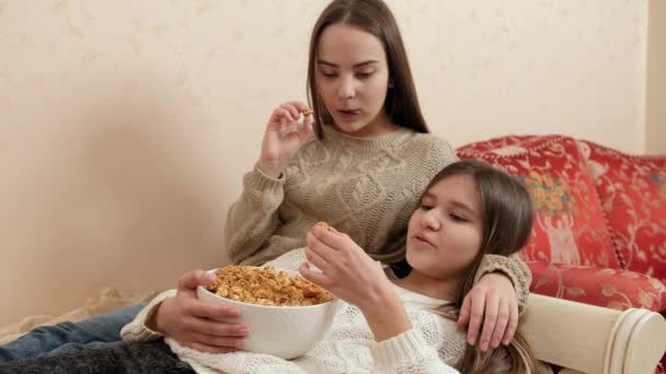 Lächelnde Teenager-Schwestern, die es sich auf dem Bett gemütlich machen und Popcorn essen. Teenager-Freundschaft und Beziehung — Stockvideo