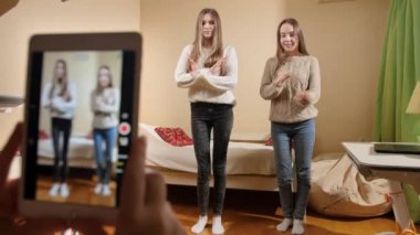 İnternete yüklemek için dans eden iki genç kızın akıllı telefondaki videosu. Modern iletişim, sosyal medya ve aygıtlar