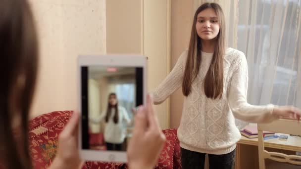 Улыбающаяся девочка-подросток танцует перед смартфоном, записывая видео для размещения в интернете. Современные коммуникации, социальные сети и гаджеты — стоковое видео