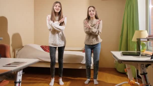 Две красивые улыбающиеся девушки танцуют и поют в спальне. — стоковое видео