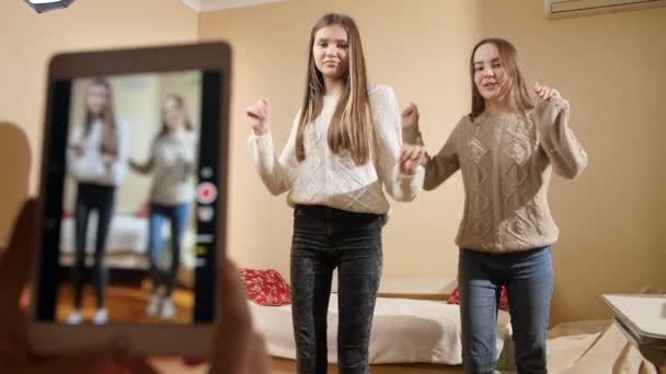 Две подружки-подростки танцуют и поют для размещения в интернете. Современные коммуникации, социальные сети и гаджеты — стоковое видео