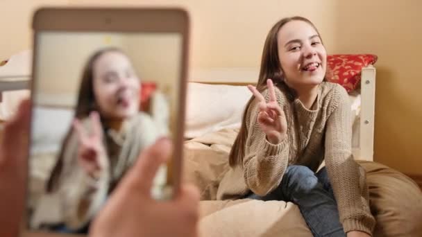 Fotografar fotografias no smartphone para mídias sociais de bela menina adolescente sorridente em casa. Comunicação moderna, mídias sociais e gadgets — Vídeo de Stock