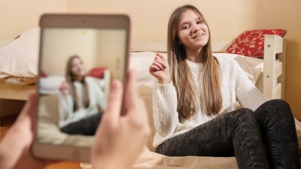 Arkadaş akıllı telefondan güzel gülümseyen genç kızın fotoğraflarını çekip internete yüklüyor. Modern iletişim, sosyal medya ve aygıtlar — Stok video