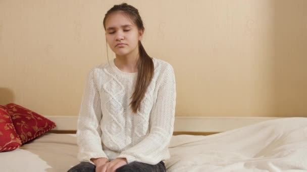 Zmęczona i wyczerpana nastolatka siedzi na łóżku i spada na poduszkę — Wideo stockowe
