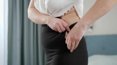 Genç obez kadın dar ve dar elbiseler giyip fermuarını kapatmaya çalışıyor. Aşırı kilo, obez kadın, diyet ve aşırı kilo sorunları kavramı