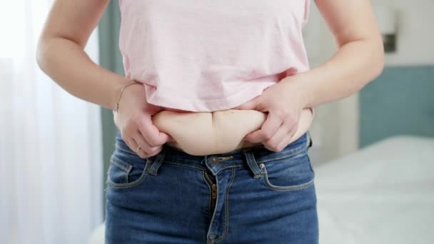 Mujer joven con sobrepeso mirando en el espejo en sus pliegues de grasa. Concepto de exceso de peso, obesidad femenina, dieta y problemas de sobrepeso — Vídeos de Stock