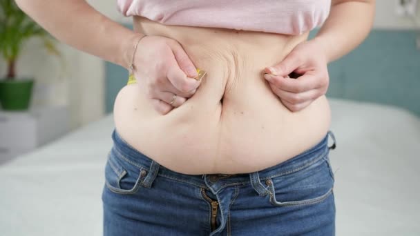 Młoda kobieta cierpi na nadwagę mierząc jej duży brzuch. Pojęcie diety, niezdrowego trybu życia, nadwagi i otyłości — Wideo stockowe