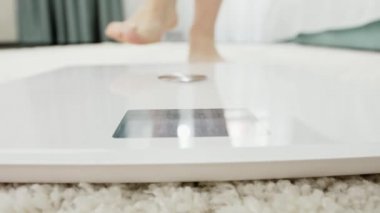 Çıplak ayaklı genç bir kadının dijital terazide yürümesi ve ayakta durması. Diyet yapma, kilo verme ve sağlıklı yaşam tarzı kavramı.
