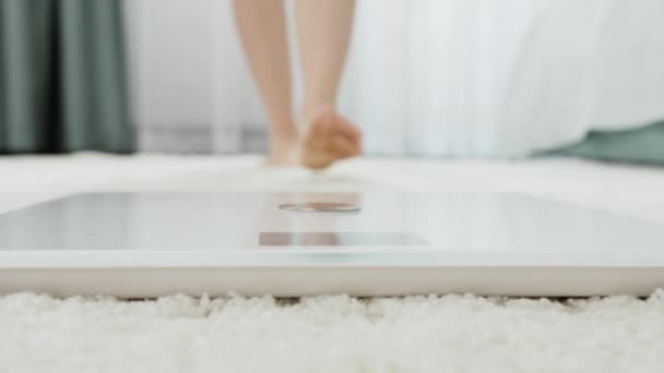 Jeune femme pieds nus debout sur des balances numériques pour mesurer son poids. Concept de régime, perte de poids et mode de vie sain. — Video