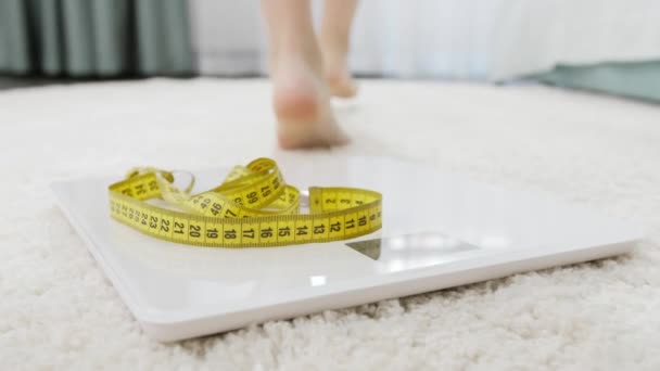 Sexy slim woman weighting on scales and walking on soft carpet in bedroom. Concept of dieting, loosing weight and healthy lifestyle. — Stock Video