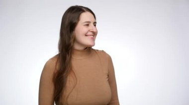 Genç bir kadının kameraya bakıp gülümsediği bir stüdyo fotoğrafı. Pozitif duygular ve yüz ifadesi